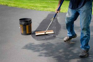 East Brunswick Sealcoating, Man shown spreading sealcoating on driveway